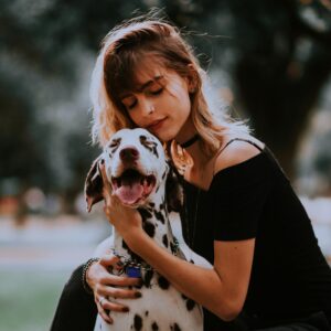 O mnie szablon 13 A young woman hugging her Dalmatian dog in a park, showcasing friendship and joy.