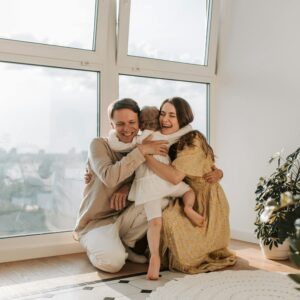O mnie szablon 14 A joyful family hugging tightly near a window, radiating warmth and togetherness.